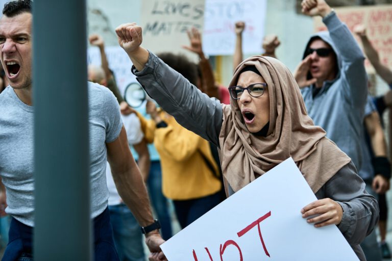 Displeased Muslim woman with raised fist shouting on anti racial