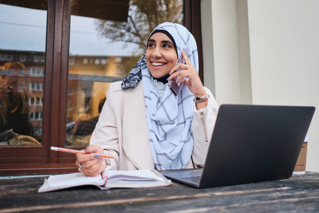 Young smiling Arabic woman in hijab happily talking on smartphon
